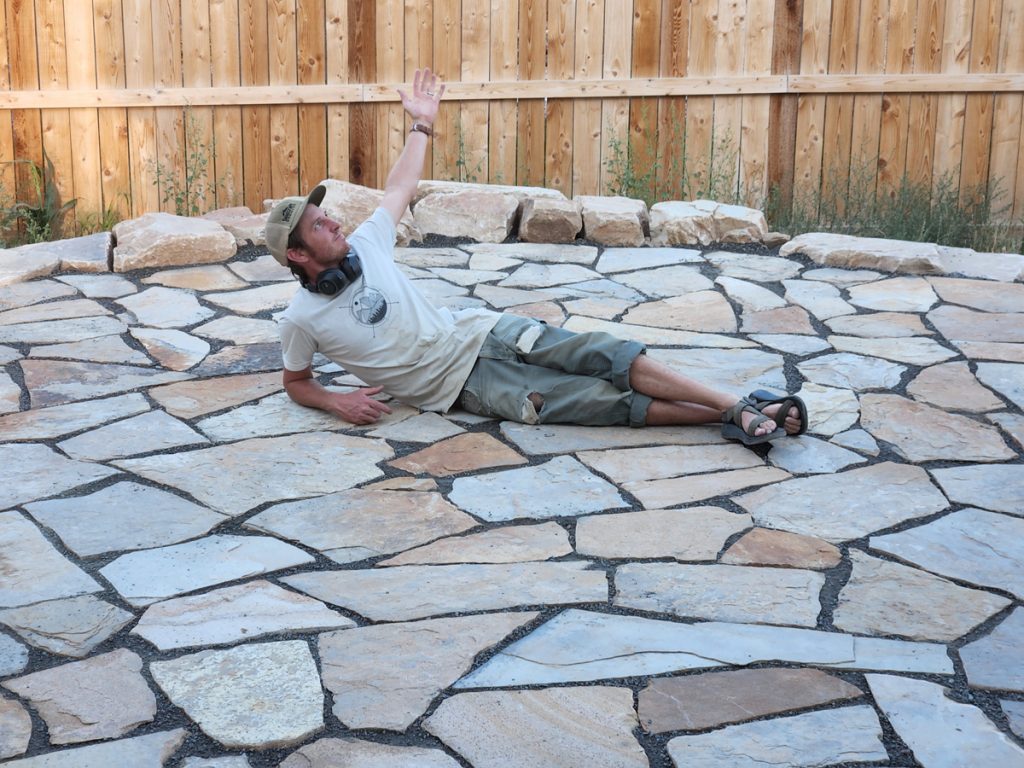 Linden Hunter from Linden Leaf Landscapes in Fort Collins laying on one of his custom flagstone patios