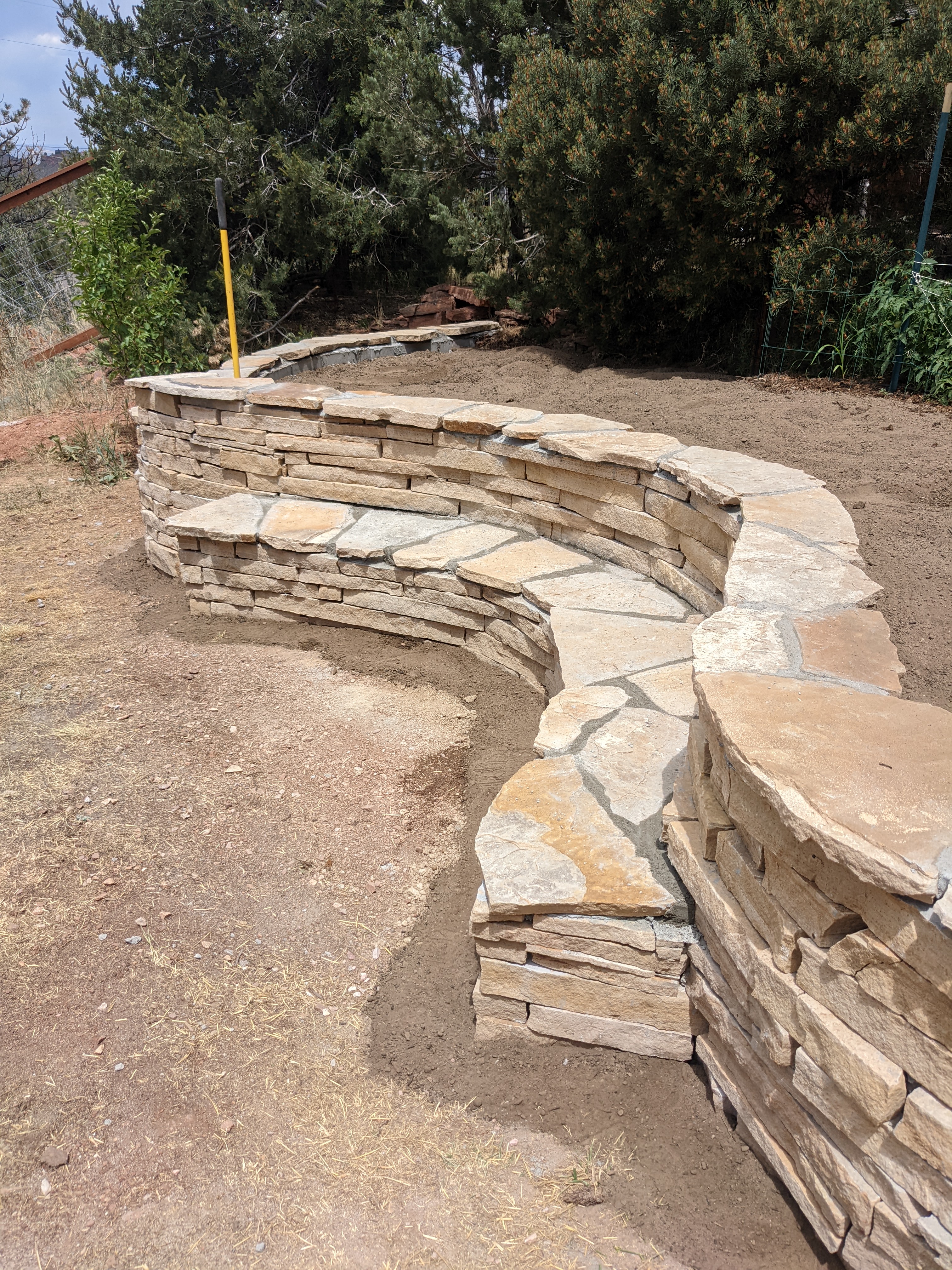 Xeriscape project with retaining wall and rock bench