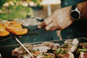 Hands at a grill with food in an outdoor kitchen in Fort Collins