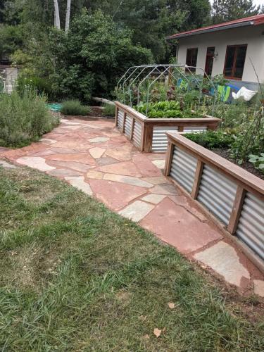 Red stone patio with large raised planter beds in Fort Collins