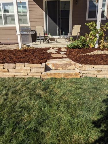 Raised stone planter garden bed with mulch in Colorado