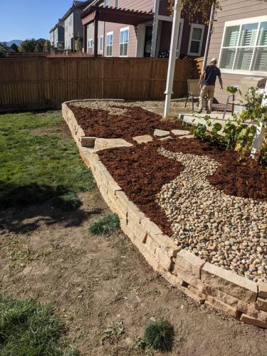 Landscape design with raised stone planter bed, steps, and mulch in Fort Collins