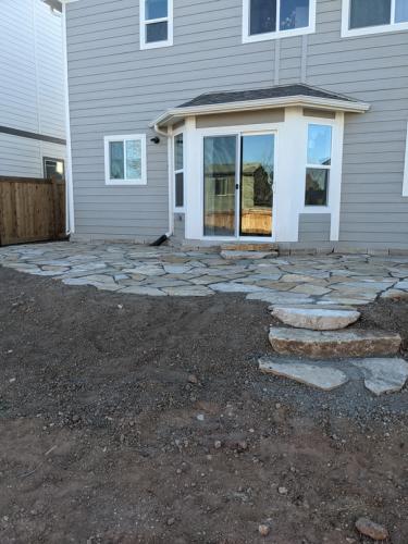 Stone back patio design with rock steps in Colorado backyard