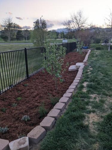 Mulch bed with fence and stone barriers in Colorado